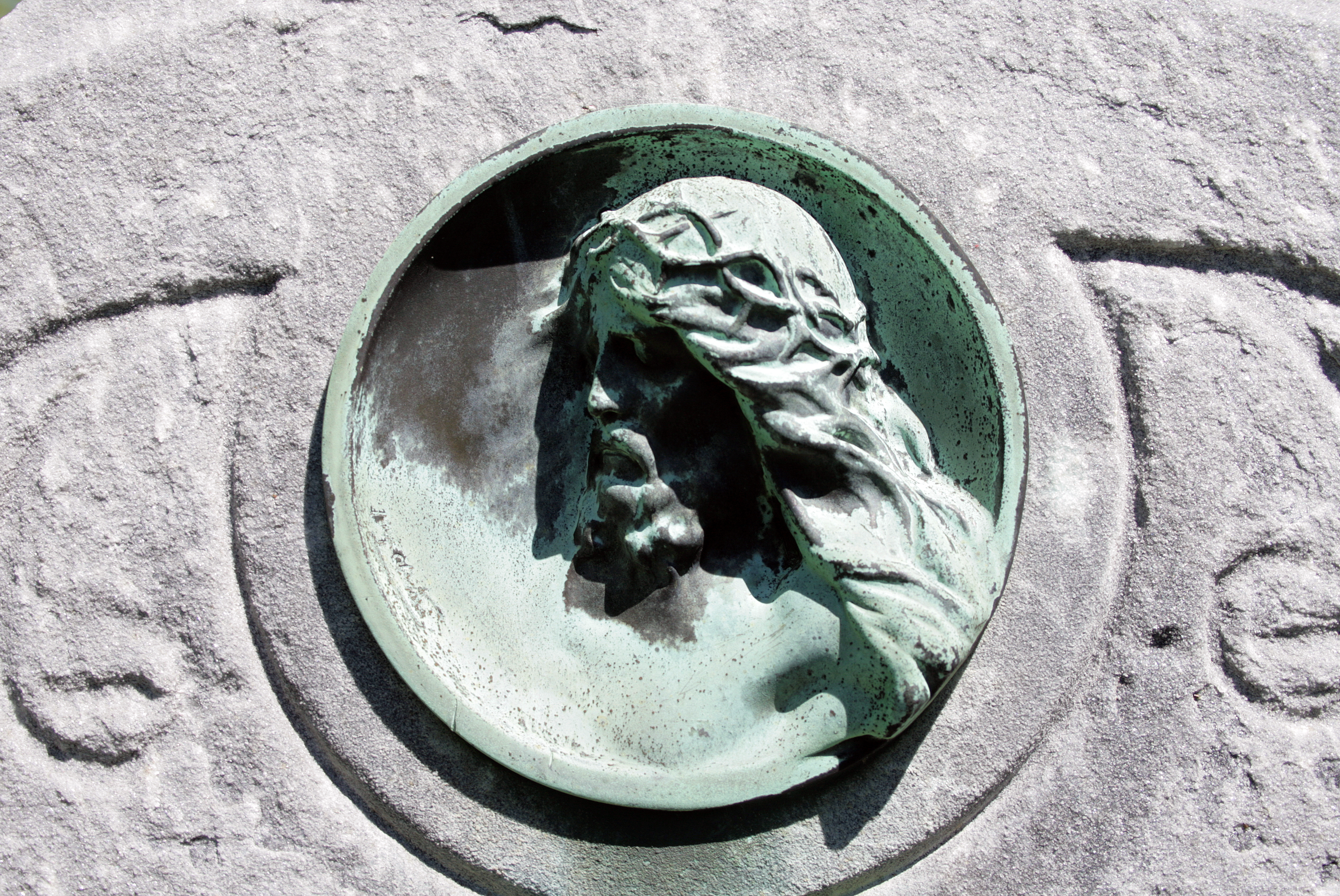 A copper Jesus portrait medallion that has turned green with age